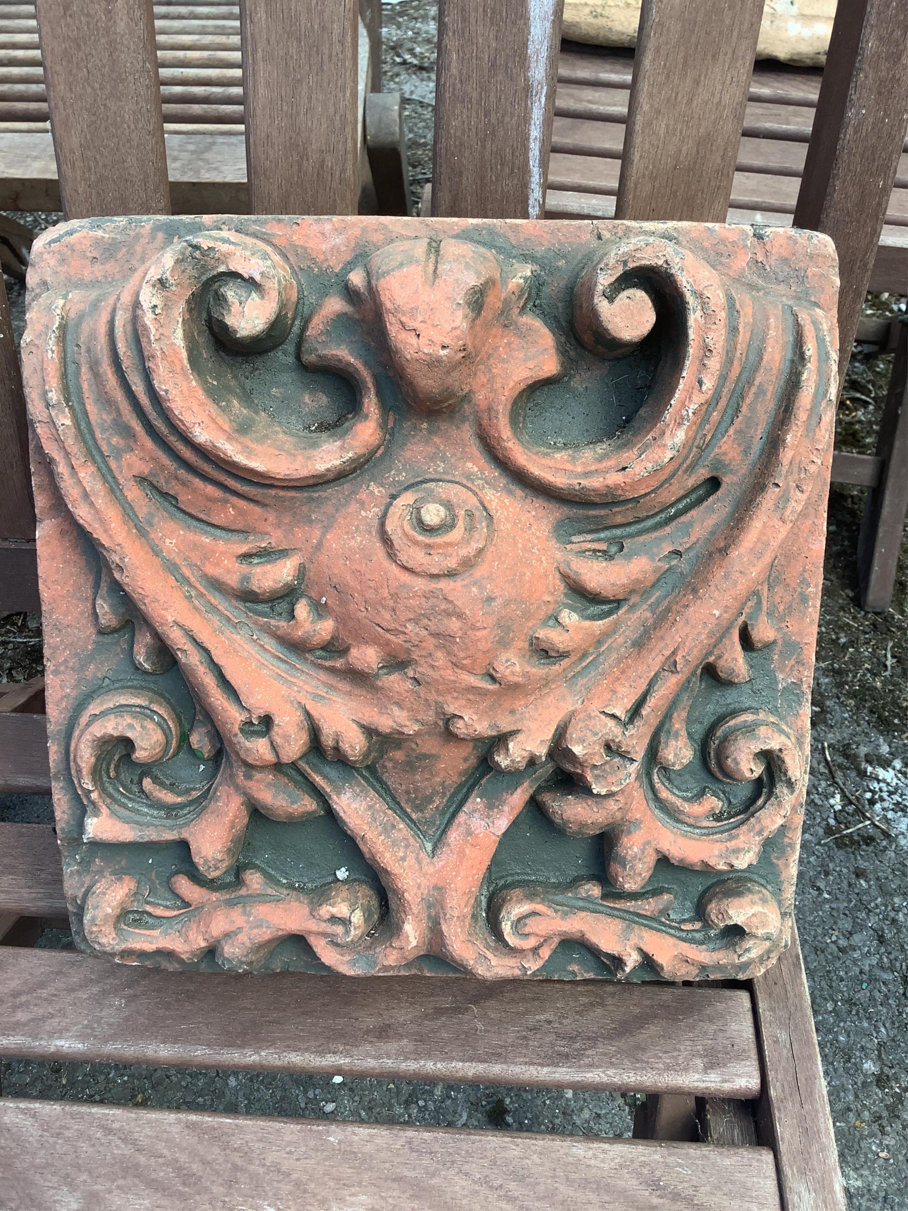 A Gothic style cast stone garden wall plaque and a terracotta tile, larger width 56cm, height 58cm